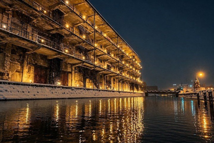 A large, illuminated building by a calm river at night. 3