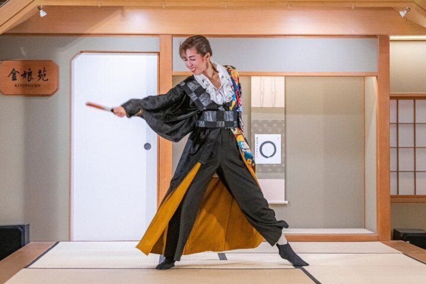 A person in traditional attire performing a martial arts move in a room with a wooden floor and a sign that reads 'KINDOUEN'. 2