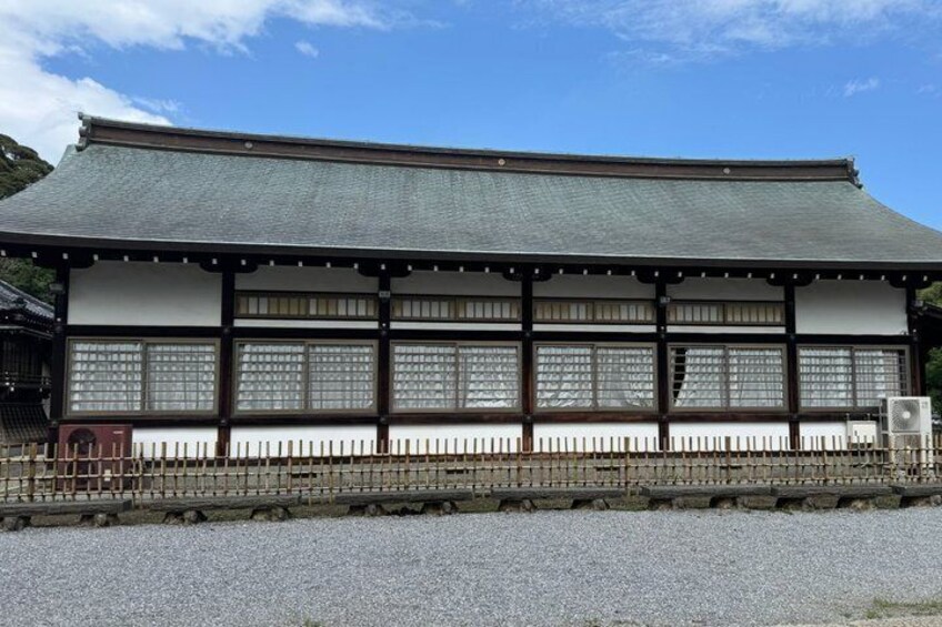 A traditional Japanese building with a tiled roof, wooden beams, and a gravel ground. 5