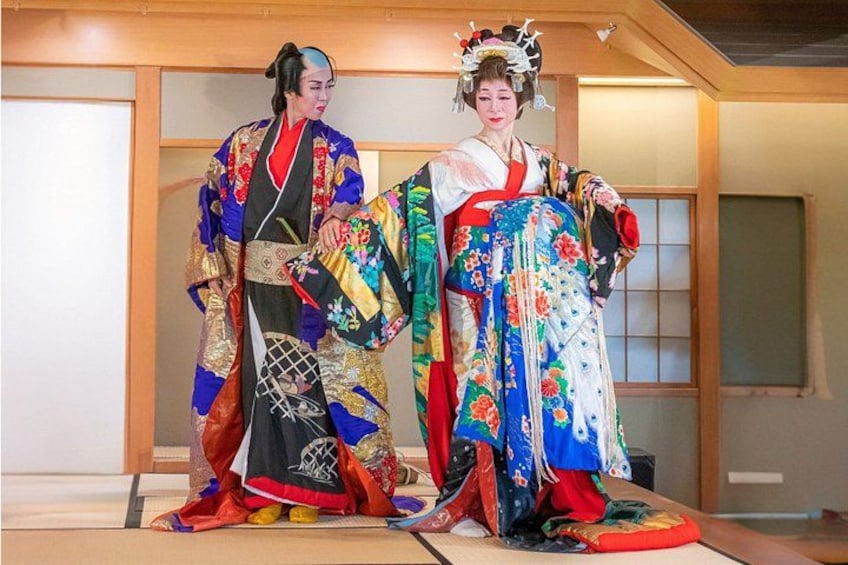 Two individuals in traditional Japanese attire, standing in a room with wooden flooring and sliding doors. 1