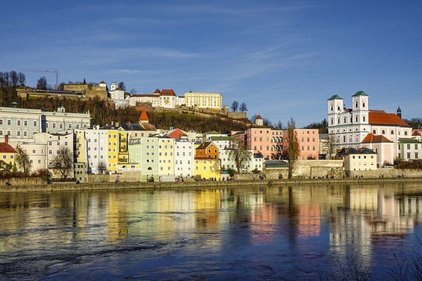 A river reflecting buildings, a hill with a castle, and a church with two towers. 5