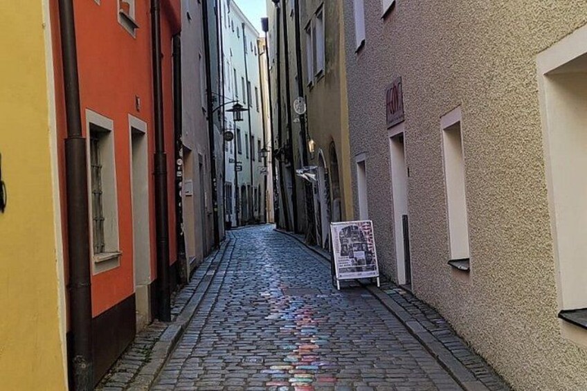 A narrow cobblestone street flanked by buildings with colorful facades. 3