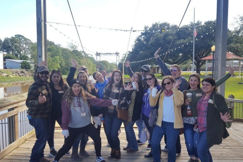 A group of people on a wooden deck with a metal railing, trees, and a building in the background. 3