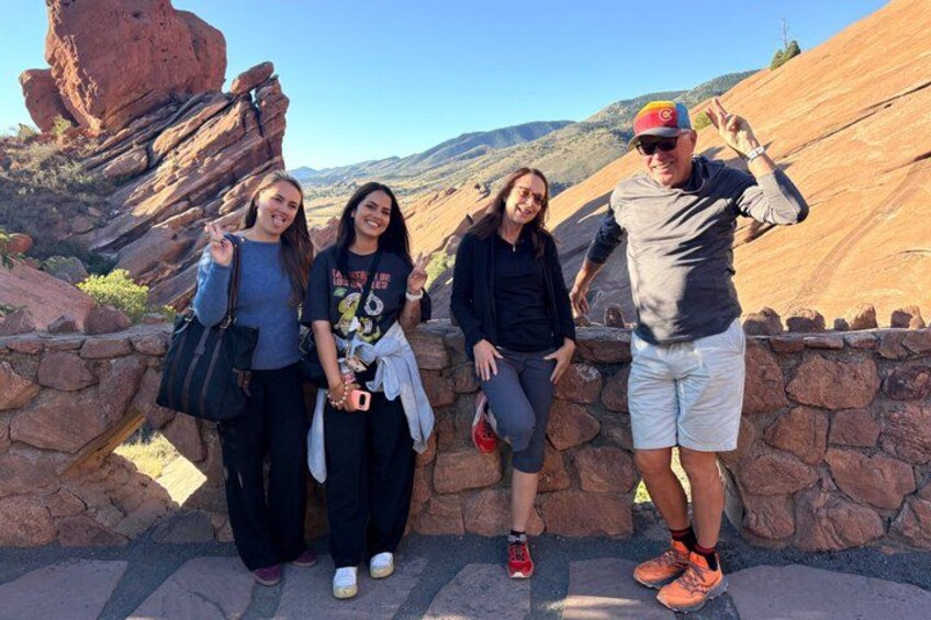 A group of people posing in a natural landscape with red rock formations and a clear sky. 4