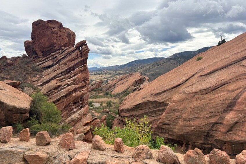 A rocky landscape with prominent red rock formations and a distant view of a valley. 5