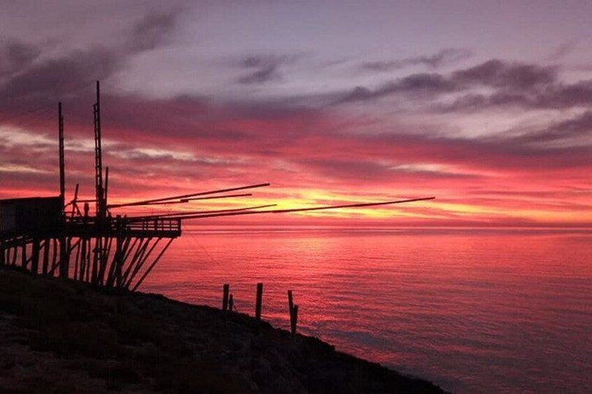 A sunset over a calm sea with a pier structure. 3