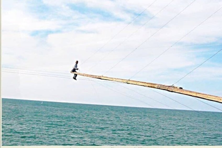 A person walking on a long wooden beam over water. 5