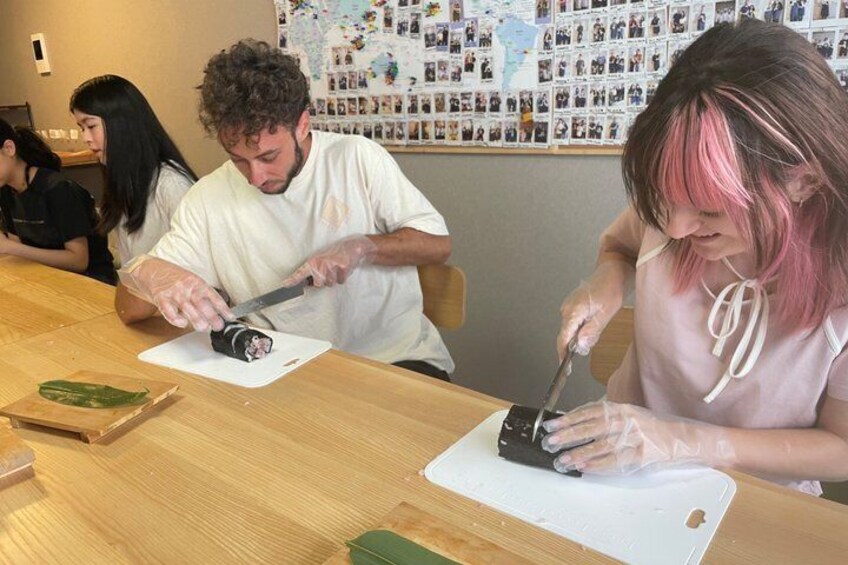 People preparing food at a wooden table with a cutting board. 3