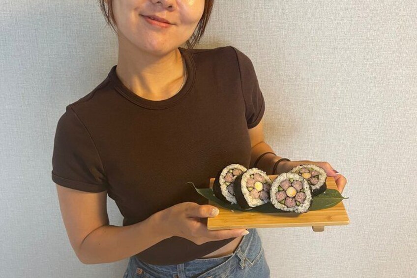 A person holding a wooden tray with sushi rolls. 2