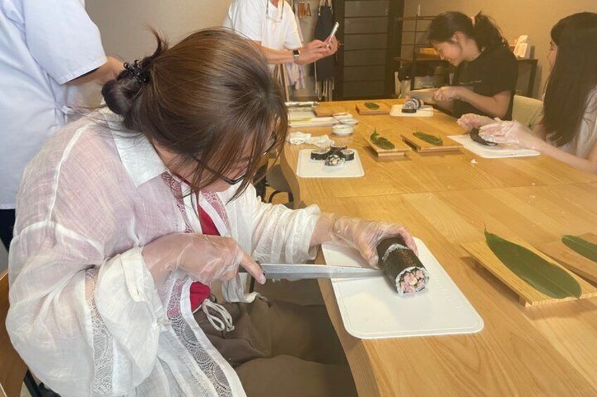 A person preparing sushi at a wooden table with various ingredients and tools. 4
