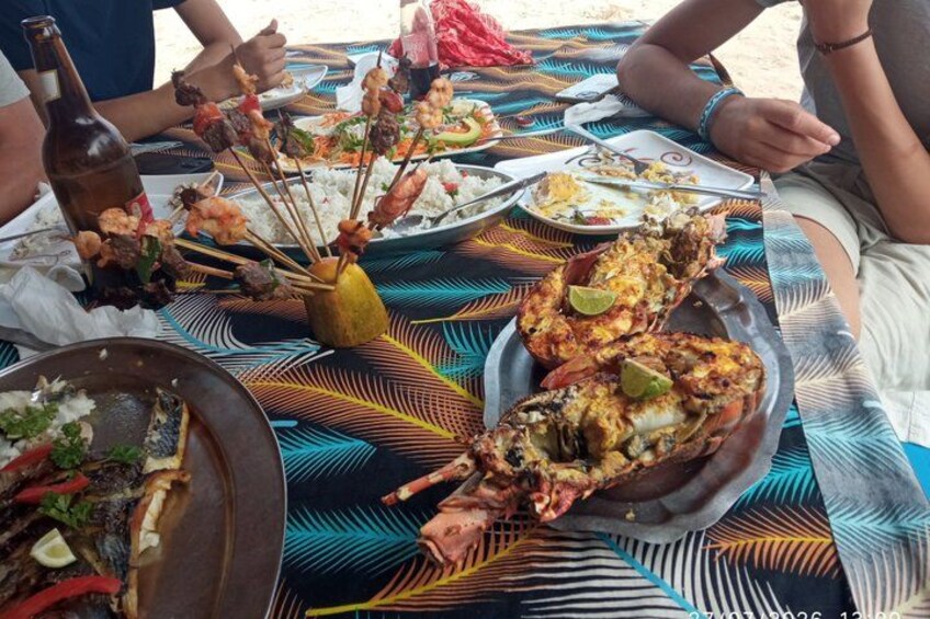 A table with seafood skewers, a lobster, and various plates of food. 2