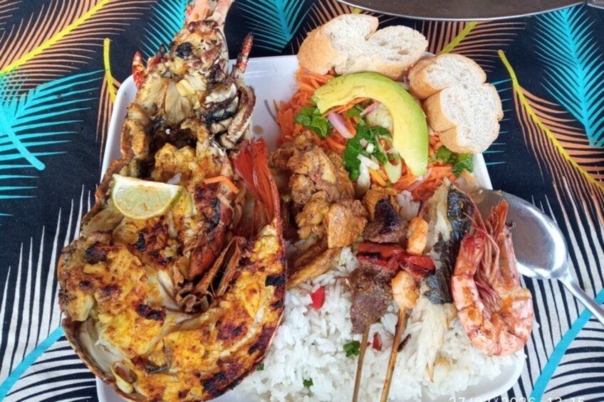 A seafood platter with grilled shrimp, lobster, and fish, served with rice and a side salad. 3