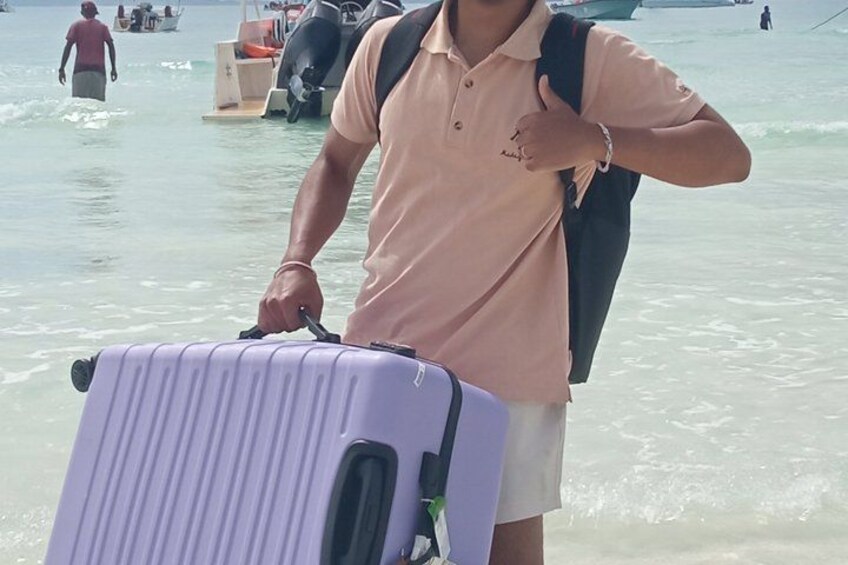 A person with a suitcase at a beach with boats and people in the background. 5