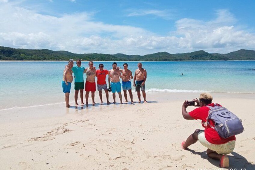 A group of people on a beach with a photographer taking their photo. 1