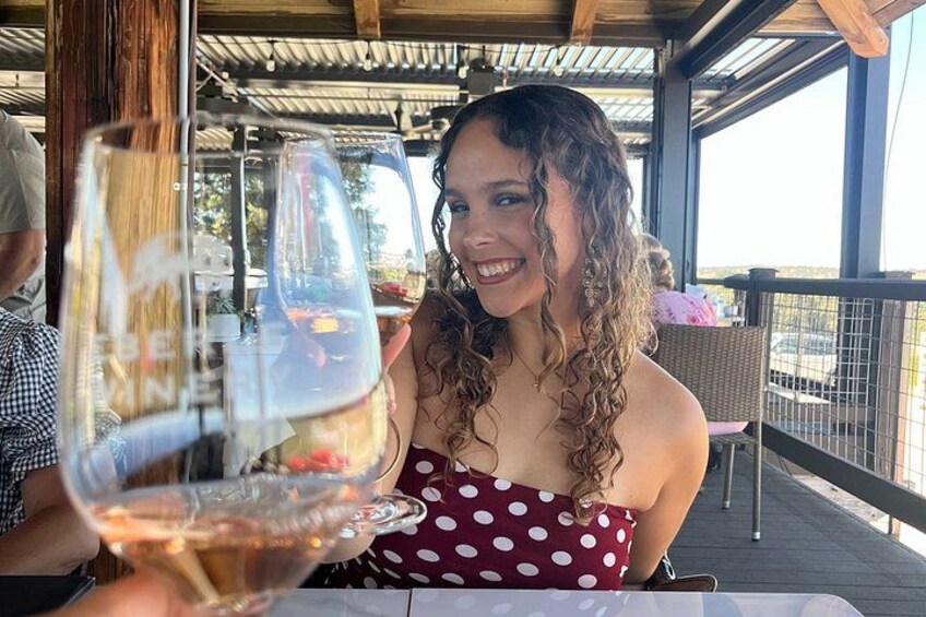 A person holding a wine glass at a table with a covered outdoor area. 3