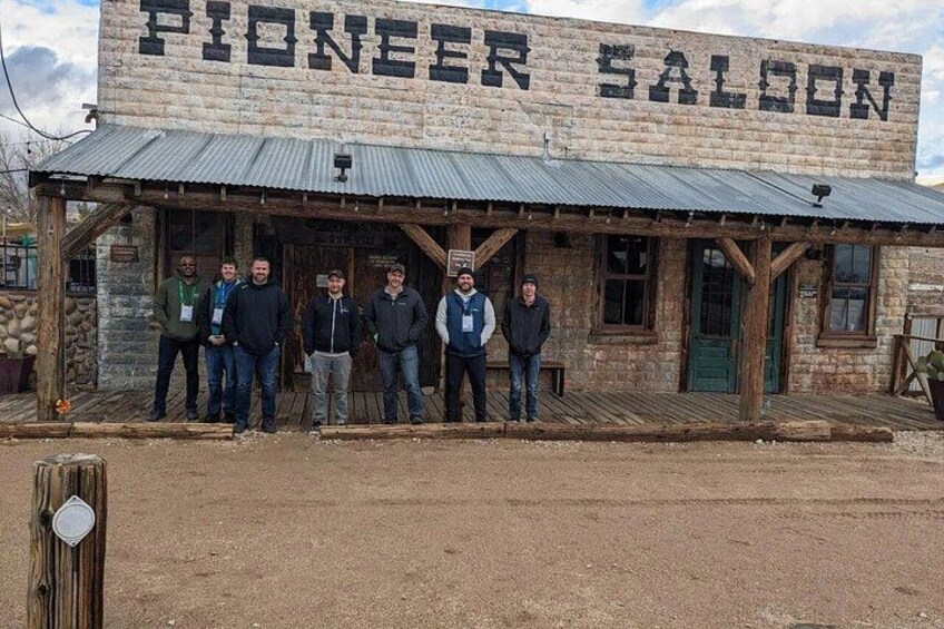 A Pioneer Saloon with a rustic exterior and a group of people standing in front. 4