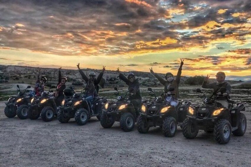 A group of people on ATVs in a desert landscape during sunset. 1