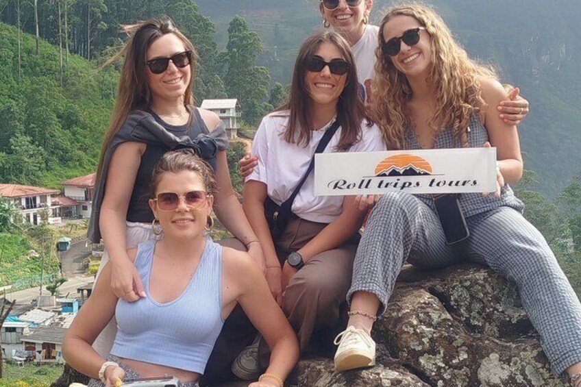 A group of people sitting on a rock with a sign that reads 'Roll trips tours.' 4