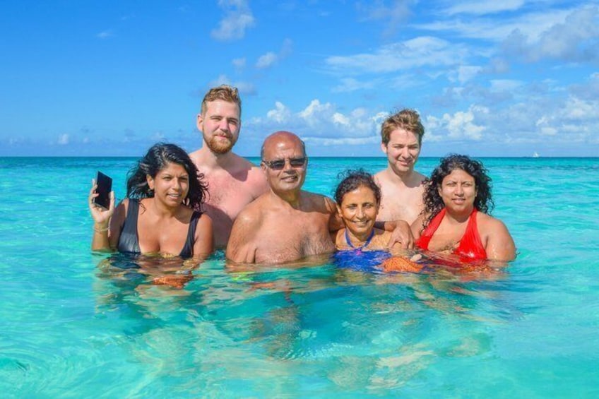 A group of people in clear turquoise water, likely on a beach. 4