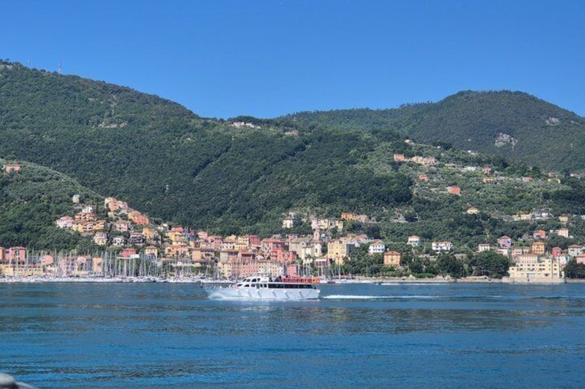 A coastal town with buildings on a hillside, a body of water, and a boat. 4