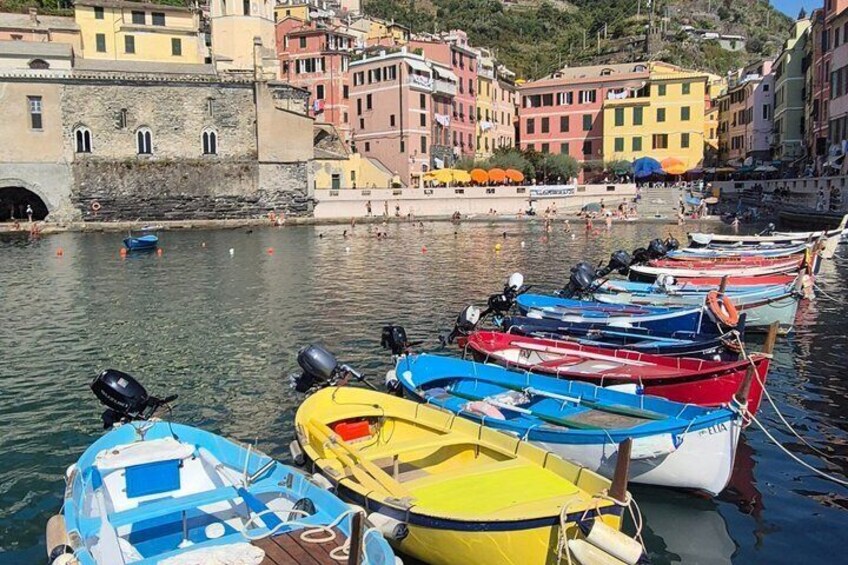 A row of colorful boats docked at a harbor with buildings in the background. 1
