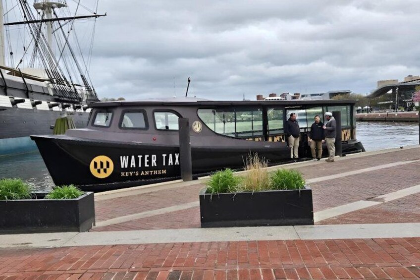A boat named 'Water Tax' docked at a marina with people standing on the deck. 4