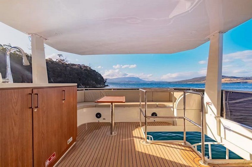 A boat deck with a wooden floor, a small table, and a metal railing. 5