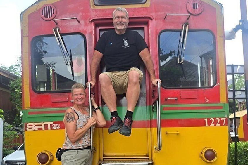 A vintage bus with two people sitting on the front steps. 2