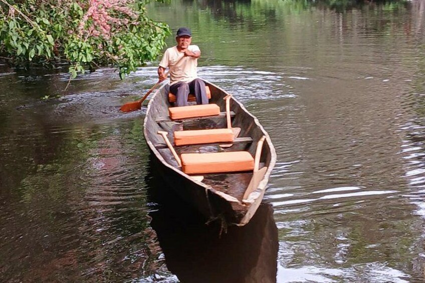 A man in a wooden boat on a calm river. 4