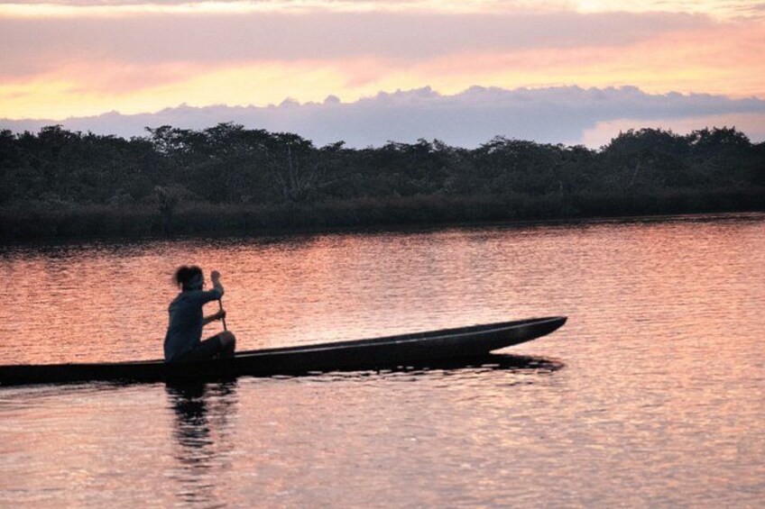 A person paddling a canoe on a calm body of water during sunset. 1