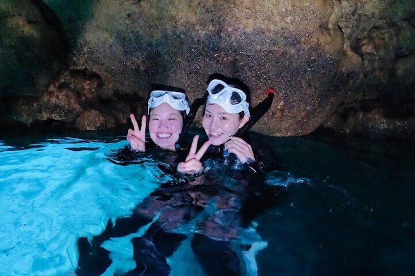 Two people in a cave with water, wearing diving gear. 4