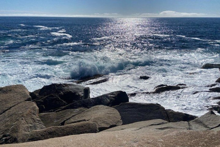 A rocky coastline with waves crashing against the rocks under a clear sky. 2