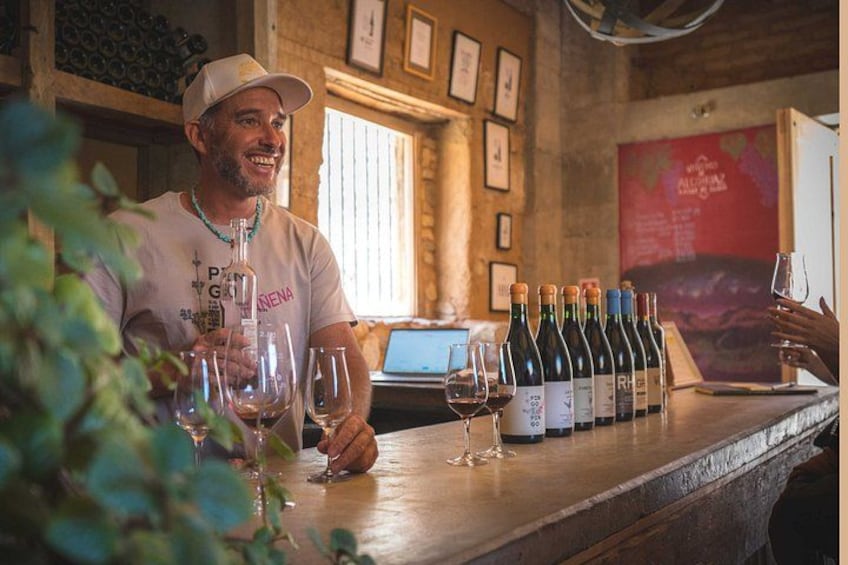 A person at a bar with wine bottles and glasses. 3