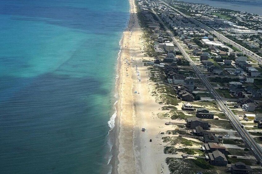 A coastal area with a beach, houses, and a road. 4