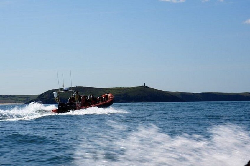 A red boat moving across calm water with a hilly landscape in the background. 3