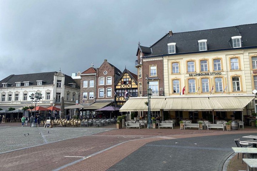 A European square with historic buildings, outdoor seating, and a cobblestone ground. 4