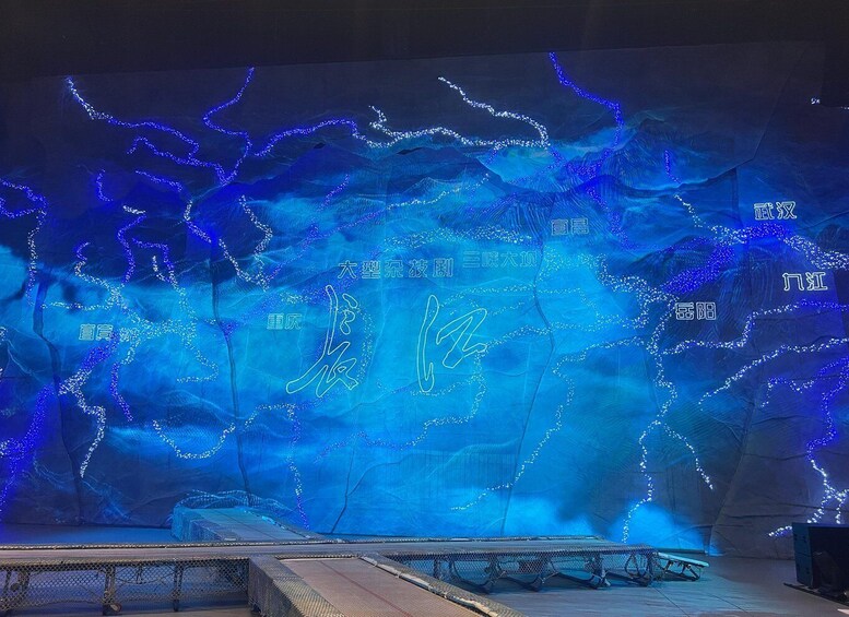 A stage with a blue-lit backdrop featuring Chinese characters and a wire mesh barrier. 3