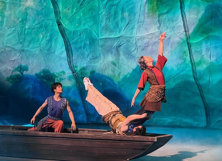 A theatrical stage with a painted backdrop of a forest, a boat, and three characters. 4