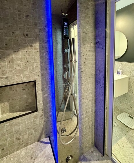 A modern bathroom with a shower, a digital control panel, and a blue light strip. 4
