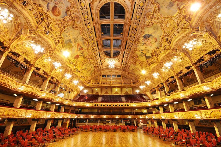 An ornate theater with golden decorations and red seating. 2