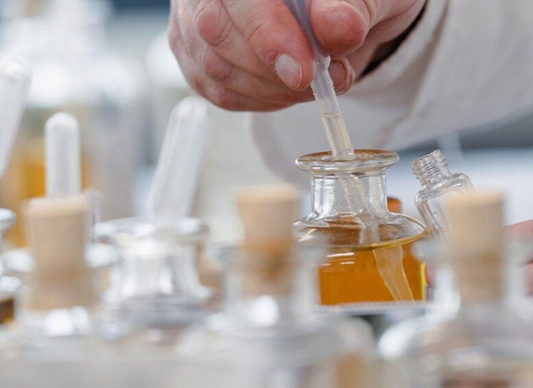 A person handling a glass container with a dropper, surrounded by similar containers. 4