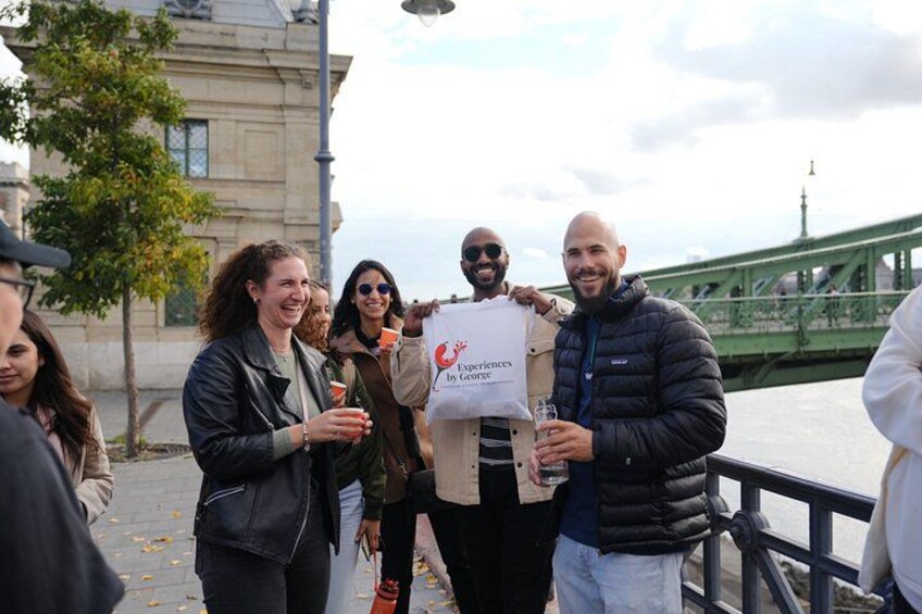 A group of people standing on a bridge with a railing, holding a sign that reads 'EXPLORE THE CITY.' 1