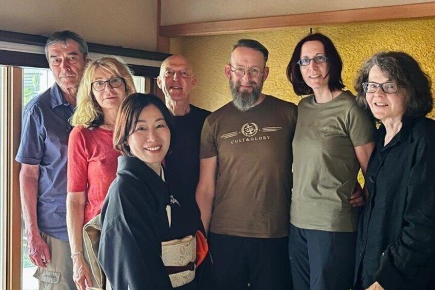 A group of people standing indoors with a yellow wall in the background. 1