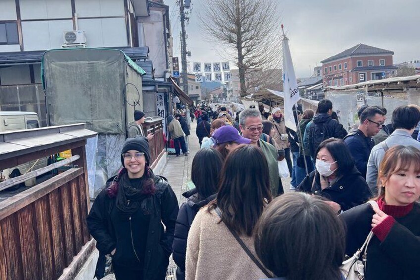 A crowded street with people walking, buildings, and a flag. 2