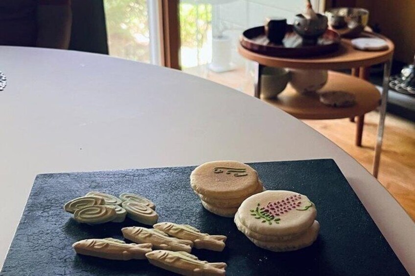 A table with macarons and a plate of cookies. 4