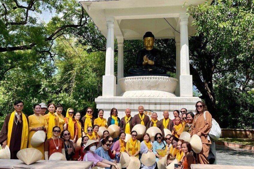 A group of people in front of a Buddha statue under a pavilion. 2