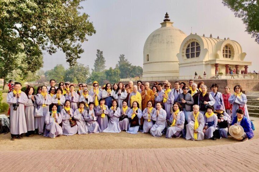 A group of people in traditional attire posing in front of a historical building with domes. 1