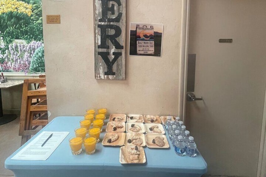 A table with food items and drinks, a sign on the wall, and a door. 5