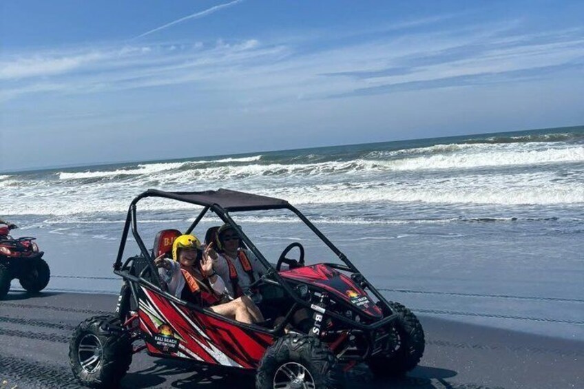 A red off-road vehicle on a beach with waves in the background. 5