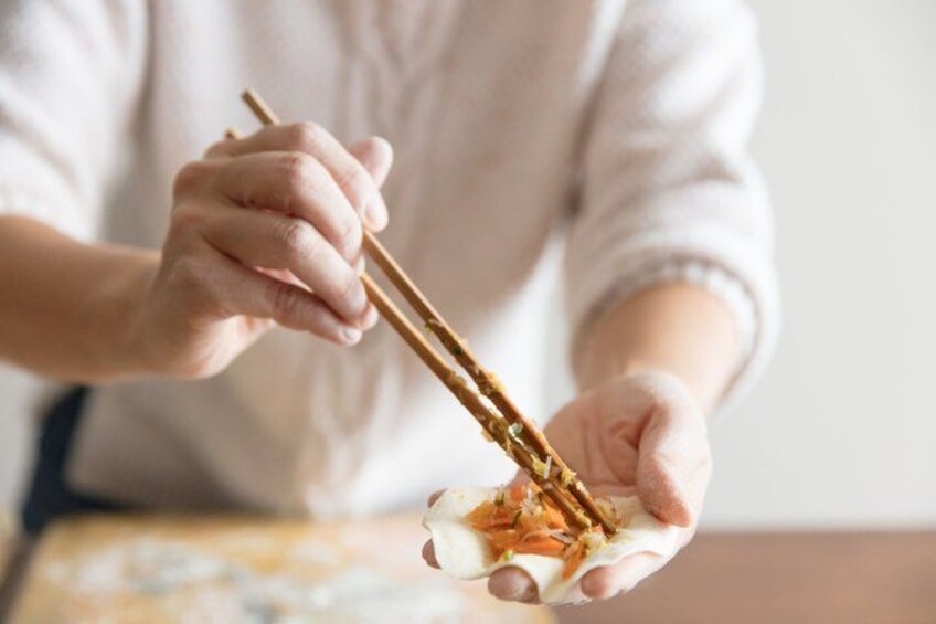 A person using chopsticks to pick up food from a plate. 3